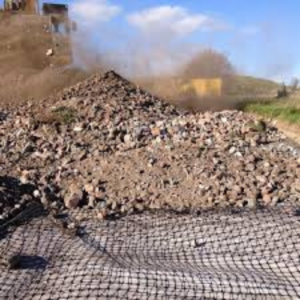 Aggregate being placed over a biaxial geogrid to create an interlocked reinforced layer for road and working platform construction.
